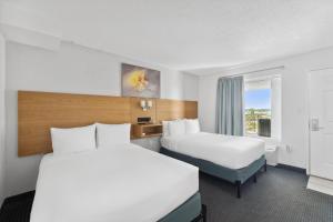 a hotel room with two beds and a window at Beachcomber Beachfront Hotel, a By The Sea Resort in Panama City Beach