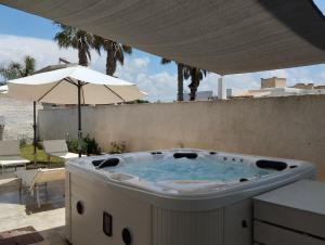 a hot tub on a patio with an umbrella at Signorino Eco Resort & Spa in Marsala