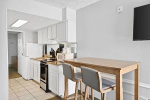 una cocina con armarios blancos y una mesa y sillas de madera. en Beachcomber Beachfront Hotel, a By The Sea Resort, en Panama City Beach