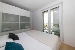 a bedroom with a white bed and a balcony at LuSea Apartment in Zadar