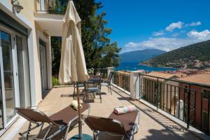 een balkon met stoelen en een parasol en uitzicht op het water bij Faos Luxury Apartments in Ayia Evfimia
