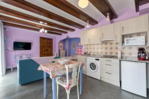 Casa Dieste Apartamentos Turísticos en Boltaña في بولتانيا: مطبخ بجدران ارجوانية وطاولة مع كراسي