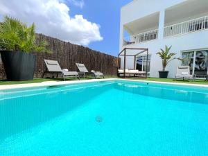 una piscina con due sedie e una casa di VILLA JULIETA a Santa Eularia des Riu