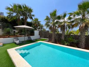 a swimming pool in a yard with palm trees at VILLA JULIETA in Santa Eularia des Riu