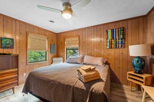 a bedroom with wooden walls and a bed and a fan at Sunny Daze KDH by Village Reality in Kill Devil Hills