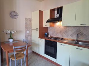 a kitchen with white cabinets and a wooden table at Alice's House - Monolocale in Pula