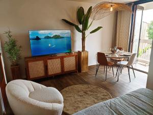 a living room with a television and a table with chairs at L'oasis du château ! "climatisé" in Gréoux-les-Bains