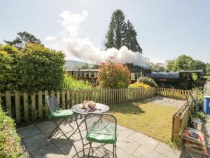 a table and chairs in a yard with a train at 7 Railway Cottages in Ulverston