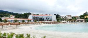 a beach with umbrellas and chairs and a hotel at Little home in Rab