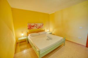a bedroom with a bed with yellow walls and two lamps at Casa Vacanza Sole & Luna in Stintino