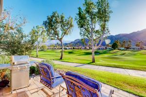 un patio avec des chaises et un grill ainsi qu'un parcours de golf dans l'établissement Palm Retreat, à La Quinta