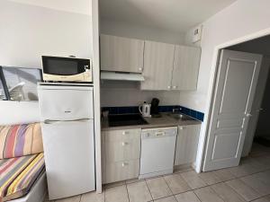 eine kleine Küche mit einem weißen Kühlschrank und einer Mikrowelle in der Unterkunft Charmant appartement T2 pour 4 personnes vue mer sables d'olonne in Saint-Jean-dʼOrbetiers