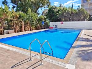 a large swimming pool with blue water at 2BR Seafront Apt in center with community pool in Larnaca