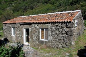 a small stone building with a red roof at Palheiro da Assomada in Faja Grande