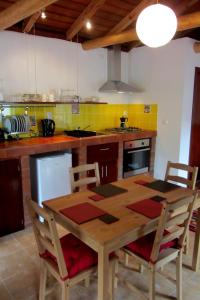 a kitchen with a wooden table and chairs at Palheiro da Assomada in Faja Grande