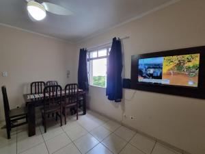 sala de estar con mesa de comedor y TV de pantalla plana en Pé na Areia, en Santos