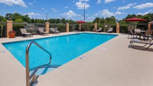 una piscina en un hotel con sillas y sombrillas en Best Western Plus Suites Greenville, en Greenville