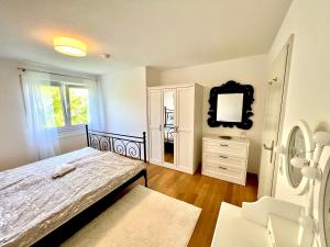 a bedroom with a bed and a mirror and a dresser at Panorama Domizil Ravensburg mit Alpenblick Balkon in Ravensburg