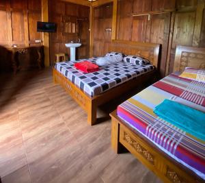 two beds in a room with wooden walls at Jogja Classic Homestay Syariah in Yogyakarta