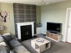 a living room with a couch and a flat screen tv at Tigh Na Mara Holiday Home - Aultbea in Aultbea