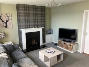 ein Wohnzimmer mit Sofa und Flachbildfernseher in der Unterkunft Tigh Na Mara Holiday Home in Aultbea