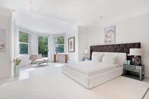 a white bedroom with a large bed and a chair at Lindfield Gardens in London