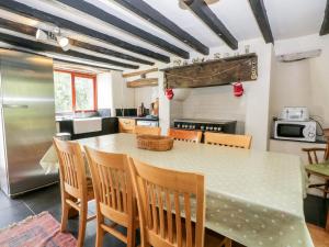 Una cocina con mesa y sillas y un refrigerador. en Moss Side Farm Cottage, en lower hawthwaite