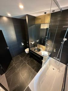 ein Bad mit einer Badewanne, einem Waschbecken und einer Dusche in der Unterkunft Primetime Hotel in Gießen