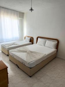 two twin beds in a room with a window at Beyaz Saray Apart Otel in Ayvalık