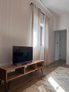 a living room with a flat screen tv on a wooden table at Casa Bizarra in Castanheira de Pêra
