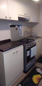 a kitchen with a stove and white cabinets at Apartamento Villarrica in Villarrica
