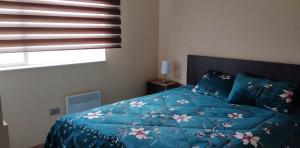 1 dormitorio con 1 cama con edredón azul y ventana en Apartamento Villarrica, en Villarrica