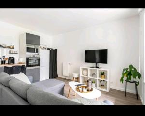 uma sala de estar com um sofá e uma mesa em Appartement Cosy à 8 min Disney 20 min Paris em Montévrain