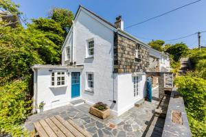 a white cottage with a blue door on a stone patio at Mermaid Cottage in Port Isaac