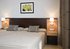een slaapkamer met 2 bedden en 2 lampen bij Hotel Castillo El Burgo in El Burgo Ranero
