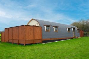 ein Haus mit einem Holzzaun neben einem grünen Feld in der Unterkunft Dragons Den in Norwich