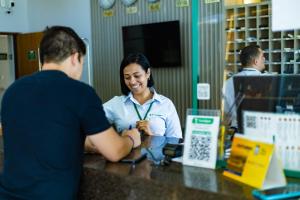 a woman talking to a man at a counter at Hotel Nacional Inn Araxá Previdência in Araxá