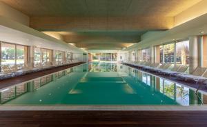 - une grande piscine avec des chaises dans un bâtiment dans l'établissement Aqualuz Troia Mar by The Editory, à Tróia