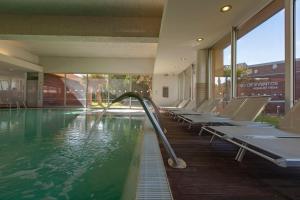 a swimming pool with a row of chairs in a building at Aqualuz Troia Mar by The Editory in Troia