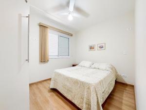 a white bedroom with a bed and a window at Apto 3 quartos, sacada, churrasqueira e garagem in Londrina