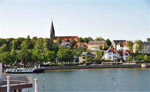 a town with a river and a boat in the water at Apartmenthaus Hafenspitze, Ap 29 "Heimathafen 29", Blickrichtung InnenstadtBinnenhafen - a72349 in Eckernförde