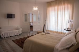 a bedroom with a bed and a couch and a chair at La Maison Dorée in Giardini Naxos