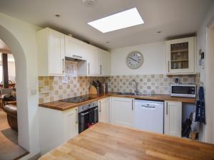 a kitchen with white cabinets and a clock on the wall at 21 Mill Green in Lyme Regis