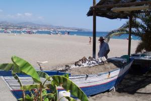 a man standing on a boat on the beach at Hostal Mediterraneo in Torre del Mar