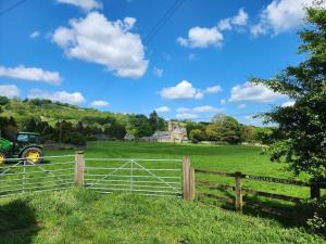 uma cerca num campo com uma casa ao fundo em Bewerley Hall farm em Harrogate