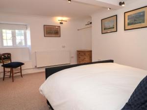 a bedroom with a white bed and a chair at Shipwrights in Brixham