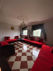 a living room with red couches and a checkered floor at Maison calme et paisible in Beni Mellal