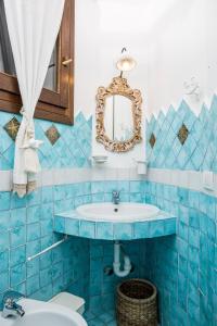 a blue tiled bathroom with a sink and a mirror at Villa Luxury Vista Mare e Piscina tra le Rocce in Cala Bitta