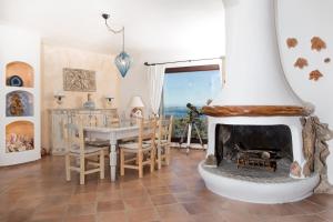 a living room with a fireplace and a table and chairs at Villa Luxury Vista Mare e Piscina tra le Rocce in Cala Bitta