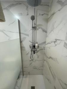een badkamer met een douche en witte marmeren muren bij Apart 3 EN PRIMERA LÍNEA DE PLAYA CON TERRAZA Y VISTAS AL MAR in Almería